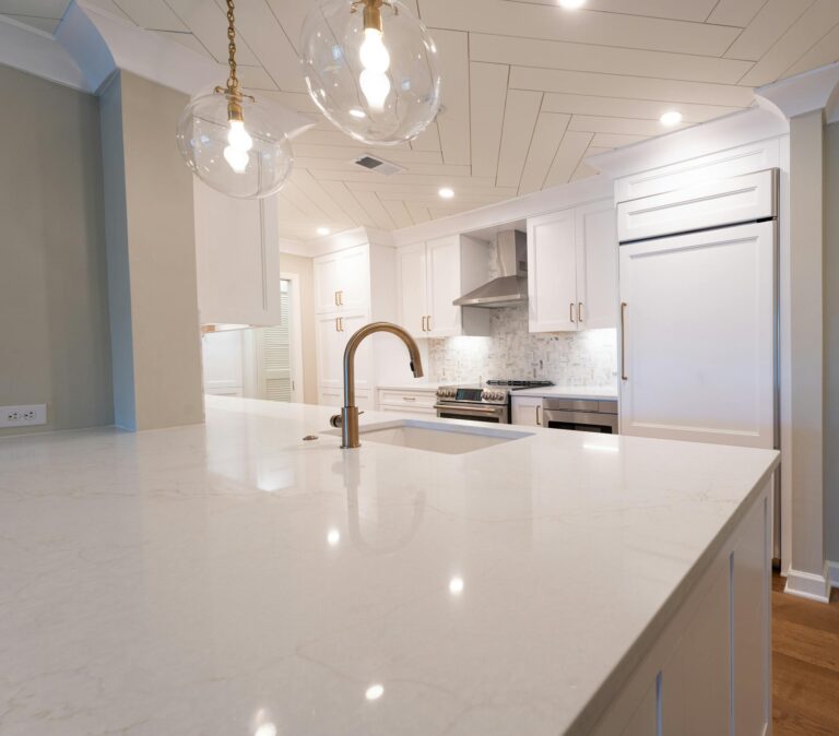 Sleek modern kitchen featuring white cabinets, marble island, and pendant lighting.